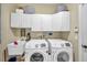 Efficient laundry room features white cabinetry, a utility sink, and modern front-loading machines at 30327 Lettingwell Cir, Wesley Chapel, FL 33543