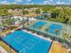 Aerial view of community tennis courts, pool, and playground surrounded by lush landscaping at 30327 Lettingwell Cir, Wesley Chapel, FL 33543