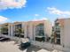 Exterior view of a condo building featuring white walls, blue trim, fenced patios, and lush palm trees at 337 Rex Pl # G, Madeira Beach, FL 33708