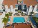 Aerial view of a community pool with lounge chairs surrounded by white condominiums and tropical landscaping at 337 Rex Pl # G, Madeira Beach, FL 33708