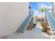 Exterior staircase leading to the condo with a glimpse of the pool and palm trees at 337 Rex Pl # G, Madeira Beach, FL 33708
