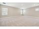 A large, carpeted bonus room with neutral walls and bright windows at 34084 Torrent Ln, Wesley Chapel, FL 33543