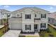 Elegant two-story home boasts a tile roof, gray exterior, and well-manicured front lawn at 34084 Torrent Ln, Wesley Chapel, FL 33543