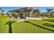 Outdoor kitchen and lounge area with a built-in grill, TV, fireplace, comfortable seating, and artificial turf at 34084 Torrent Ln, Wesley Chapel, FL 33543