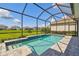 Inviting screened pool boasts blue tile accents and sunny backyard views at 34084 Torrent Ln, Wesley Chapel, FL 33543