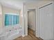 Bright bathroom featuring a jacuzzi tub with a window, classic columns, tile floors and a separate toilet room at 38824 Raiser Rd, Dade City, FL 33525