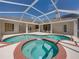 This patio has a screened-in pool and hot tub, along with white wicker furniture on the surrounding concrete patio at 38824 Raiser Rd, Dade City, FL 33525