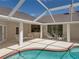This backyard features a covered patio with a screened-in pool, hot tub, and white wicker furniture for relaxing at 38824 Raiser Rd, Dade City, FL 33525