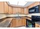 A kitchen featuring wooden cabinets, granite countertops, a stainless steel sink, and black appliances at 4900 Brittany S Dr # 1810, St Petersburg, FL 33715
