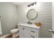 Charming half bathroom with a modern vanity, decorative mirror, and shiplap walls at 4914 Country Hills Dr, Tampa, FL 33624