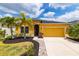 Inviting yellow home featuring a 2-car garage, well-manicured lawn and lush, mature palm trees at 5048 Inshore Landing Dr, Apollo Beach, FL 33572