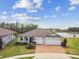 Stunning aerial view of a home near a tranquil lake, showcasing the manicured lawn and three-car garage at 5670 Shorebird Br, Land O Lakes, FL 34638