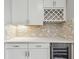 Stylish bar area featuring white cabinets, a wine rack, tile backsplash, and wine cooler at 5670 Shorebird Br, Land O Lakes, FL 34638