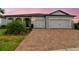 Charming single-story home featuring a brick driveway, two-car garage and beautifully landscaped front yard under a pink sky at 5670 Shorebird Br, Land O Lakes, FL 34638