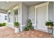 Inviting front porch with brick flooring, white door and trim, plus lush greenery and potted plants on display at 5670 Shorebird Br, Land O Lakes, FL 34638