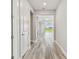 Hallway with white trim and wood-look flooring that leads to an open living area with sliding glass doors at 5670 Shorebird Br, Land O Lakes, FL 34638
