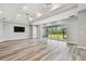Spacious living room with light wood floors, large windows, and tray ceiling with modern fans at 5670 Shorebird Br, Land O Lakes, FL 34638
