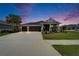 Beautiful single-story home with a three-car garage, landscaped front yard, and a cozy porch, all under a twilight sky at 5828 Clairwood Ct, Palmetto, FL 34221