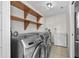 Well-lit laundry room featuring wooden shelving above modern washer and dryer units at 6415 13Th N Ave, St Petersburg, FL 33710