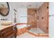 Bathroom featuring a marble-trimmed tub and glass shower with wood-look flooring at 6442 Lake Sunrise Dr, Apollo Beach, FL 33572