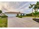 Charming single-story home featuring a well-manicured lawn, mature palms, and a circular driveway at 6442 Lake Sunrise Dr, Apollo Beach, FL 33572