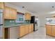Open kitchen view featuring stainless steel appliances, light wood cabinets, and an open floor plan at 6442 Lake Sunrise Dr, Apollo Beach, FL 33572