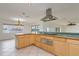 Open kitchen view with stainless steel appliances, light wood cabinets and chandelier lit dining area at 6442 Lake Sunrise Dr, Apollo Beach, FL 33572