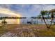 Waterfront view with lush palms, a private dock and boat lift overlooking the serene waterway at sunset at 6442 Lake Sunrise Dr, Apollo Beach, FL 33572