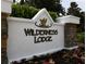 Community sign for Wilderness Lodge with stacked stone and colorful flower bed landscaping below at 7031 Kendall Heath Way, Land O Lakes, FL 34637