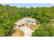 Aerial view of one story home surrounded by lush trees and a lengthy concrete driveway at 7340 West Dr, Wesley Chapel, FL 33544