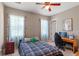 Comfortable bedroom with large windows, ceiling fan, and a computer desk setup at 7340 West Dr, Wesley Chapel, FL 33544