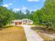 Stately one story home with a long driveway and two-car garage surrounded by lush trees at 7340 West Dr, Wesley Chapel, FL 33544
