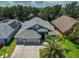 Aerial view of home featuring a spacious roof, three car garage and lush landscaping at 7657 Nottinghill Sky Dr, Apollo Beach, FL 33572