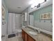 Bright bathroom with granite countertop, shower-tub combination, and decorative herringbone wallpaper at 7657 Nottinghill Sky Dr, Apollo Beach, FL 33572