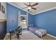 Blue bedroom offering a bed, window views of the backyard, and sports-themed decor at 7657 Nottinghill Sky Dr, Apollo Beach, FL 33572