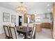 Bright dining room features modern light fixture, dining table and chairs next to kitchen with island at 7991 1St S Ave, St Petersburg, FL 33707