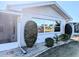 Side view of a white home featuring a screen door, lush landscaping, and ample natural light at 810 Bluewater Dr, Sun City Center, FL 33573
