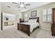 Comfortable main bedroom featuring neutral tones, ceiling fan, carpeted floors, and a bathroom at 8320 Bluevine Sky Dr, Land O Lakes, FL 34637