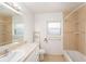 Bright bathroom with beige tile, single sink vanity, a large mirror, and a shower-tub combo at 109 S Nimbus Ave, Clearwater, FL 33765