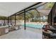 Covered outdoor living area with a pool, grill, lounge seating and leafy views at 11709 N Armenia Ave, Tampa, FL 33612