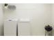 Well-lit laundry room with a modern washer and dryer, shelf, and decorative plant at 13167 Violet Flame Ave, Wimauma, FL 33598