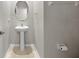 A minimalist powder room with a pedestal sink, mirror, and neutral color scheme at 13380 Great Plains Dr, Riverview, FL 33579