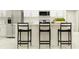 Modern kitchen with white cabinets, stainless steel appliances, and stylish black bar stools at 15250 Rainbow Quartz St, Wimauma, FL 33598