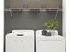 Functional laundry room with white washer and dryer, storage shelves, and a decorative plant at 15250 Rainbow Quartz St, Wimauma, FL 33598