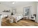 Bright bedroom features a beautiful white wooden bed frame, light wood floors, and two sunny windows at 15704 Mifflin Ct, Tampa, FL 33647