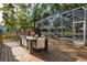 Outdoor deck featuring a dining table with seating, a screened-in pool area, and lush greenery at 15704 Mifflin Ct, Tampa, FL 33647