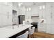 A modern kitchen boasts white cabinetry, stainless steel appliances, and a beautiful quartz countertop island at 15704 Mifflin Ct, Tampa, FL 33647