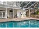 Backyard pool with screened enclosure, brick patio, and view of the multi-story white home at 15704 Mifflin Ct, Tampa, FL 33647