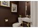 Stylish powder room featuring dark walls, modern art, and a unique sink with elegant gold hardware at 15704 Mifflin Ct, Tampa, FL 33647