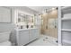Modern bathroom featuring a double vanity, illuminated mirror, and a glass-enclosed shower with neutral-toned tiles at 1715 N Alexander Rd, Tampa, FL 33603